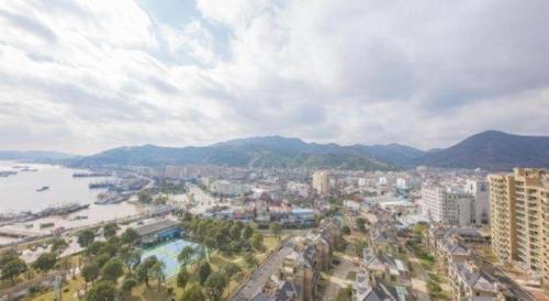 an aerial view of a city with a river and mountains at New Century Hotel Ningbo Xiangshan Shipu in Shipuzhen