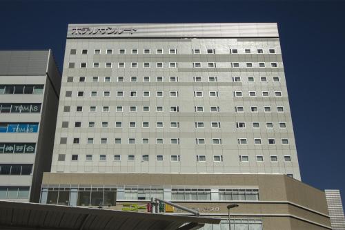 a tall white building with a sign on it at Hotel Sunroute Chiba in Chiba