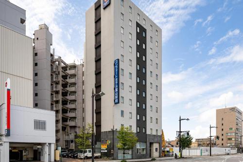 a tall white building with a blue sign on it at Comfort Hotel Toyama in Toyama
