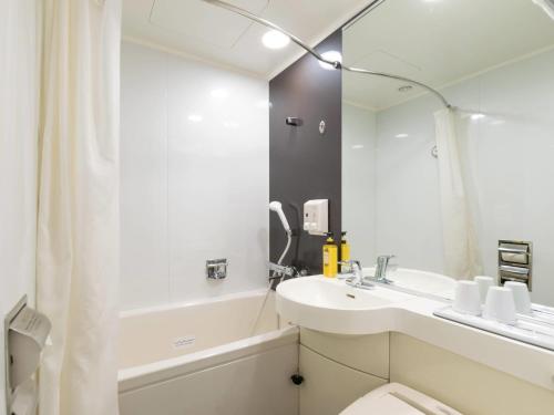 a bathroom with a sink and a toilet and a mirror at Comfort Hotel Toyama in Toyama