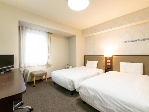 a hotel room with two beds and a television at Comfort Hotel Toyama in Toyama