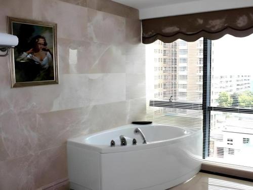 a white bath tub in a bathroom with a window at Manhatton Hotel Beihai in Dianbailiao