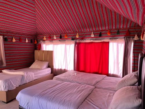 una camera da letto con due letti e tende rosse di Rum Tale Camp a Wadi Rum