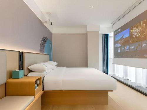 a bedroom with two beds and a projection screen at City Comfort Inn Wuhan Hankou Railway Station West Square in Wuhan