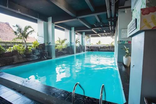 una gran piscina en un edificio con agua azul en Grand Darmo Suite by AMITHYA, en Surabaya