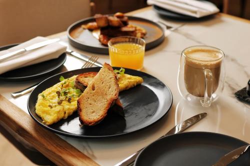 een tafel met twee borden eieren en toast en een glas koffie bij The Max Hotel Sandton in Johannesburg