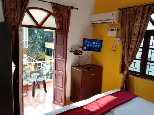 AguadaAlexmarie Guest house 5 min to candolim Beach的一间卧室，配有一张床和一扇通往阳台的门