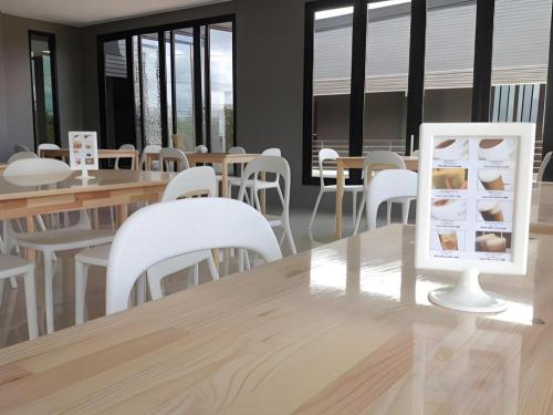a dining room with white chairs and tables and a tablet on a table at Nangfa Mini Hotel in Ban Pa Kwao