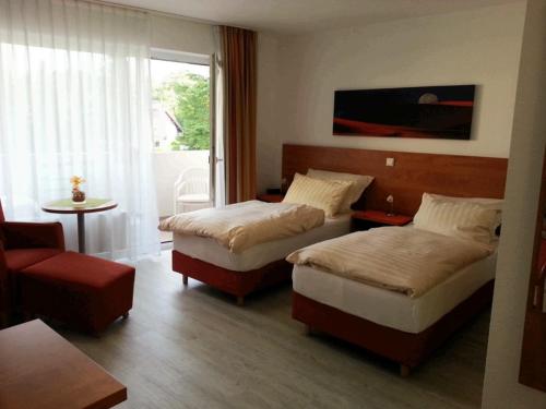 a hotel room with two beds and a chair at Sonniges Studio im Haus Deutsch Krone in Bad Rothenfelde