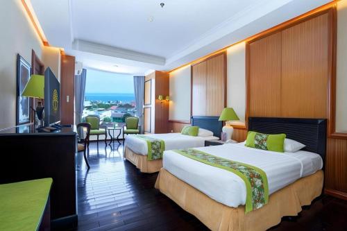 a hotel room with two beds and a table at Gran Senyiur Hotel in Klandasan Kecil