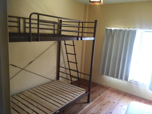 two bunk beds in a room with a window at Guest House & Cafe Ohana in Imabari