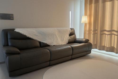 a leather couch with a blanket on top of it at 인덕원스테이 27 in Mabun-ni