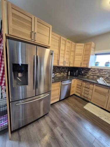 een keuken met een roestvrijstalen koelkast en houten kasten bij Comfort Tenacity in Yellowknife