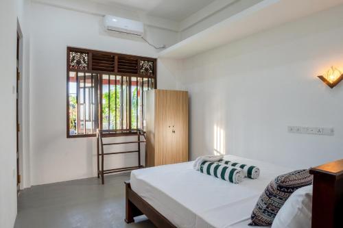a white bedroom with a bed and a window at Villa Sky View Hikka in Hikkaduwa