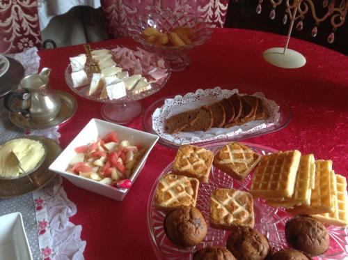 a red table topped with plates of bread and waffles at La Demeure aux Hortensias in Pleurtuit