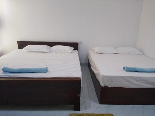 two beds in a room with white sheets and blue pillows at සදෙව් Villa in Anuradhapura
