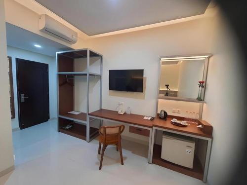 une pièce avec un bureau avec un miroir et une chaise dans l'établissement Kenari Asri Hotel, à Kudus