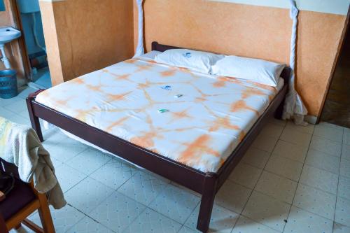 a bed with an orange and white comforter on it at Ogalis K-coast Hotel in Mtwapa