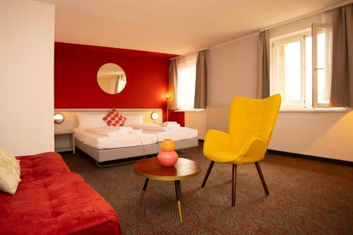 una stanza d'albergo con un letto e una sedia gialla di Hessenland Hotel Kassel Innenstadt by Stay Awesome a Kassel