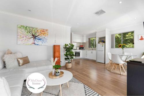 a living room with a white couch and a kitchen at Lovely Renovated 2BR Townhouse WiFi Parking in Sturt