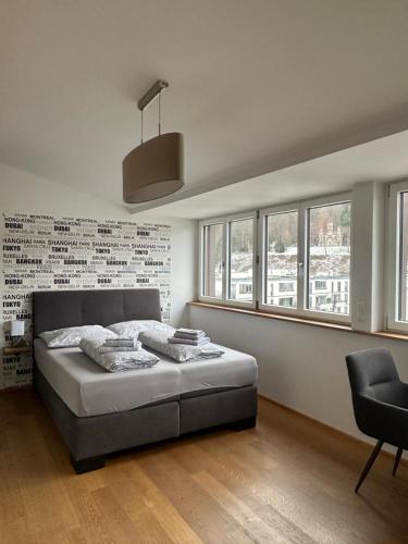 a bedroom with a bed and a chair and windows at Moderne Apartments in attraktivem Altbau in Freiburg im Breisgau