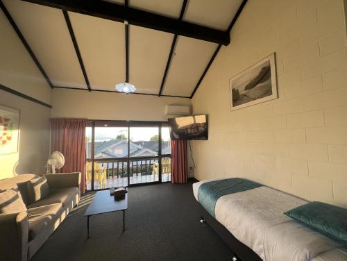 a bedroom with a bed and a couch and a tv at Mountain View Motel in Taupo