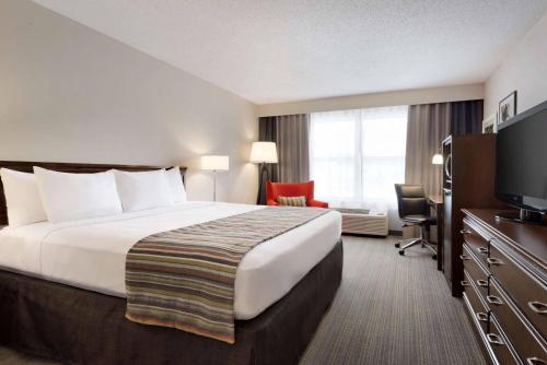 a hotel room with a bed and a television at Country Inn & Suites by Radisson, Houghton, MI in Houghton