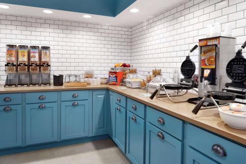 Country Inn & Suites by Radisson, Houghton, MI في هوتون: مطبخ مع الدواليب الزرقاء والبلاط الأبيض