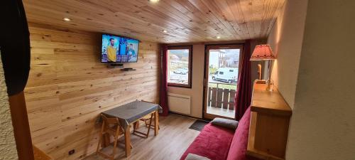 a room with a wooden wall with a tv and a table at Le Bois Joli en Chartreuse in Saint-Pierre-de-Chartreuse