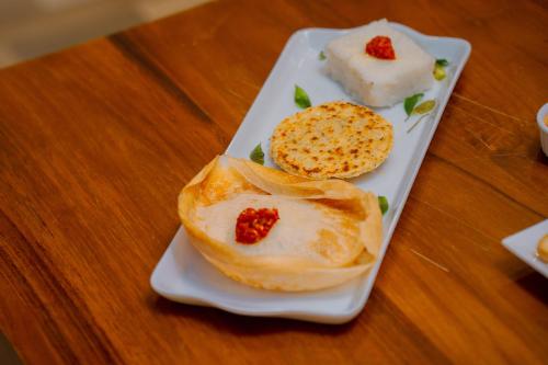 une plaque blanche avec de la nourriture sur une table en bois dans l'établissement Emerald Resort Hikkaduwa, à Hikkaduwa