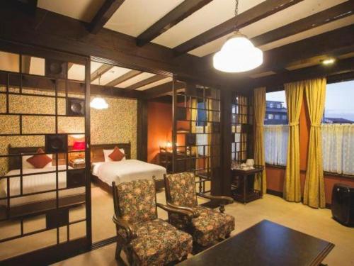 une chambre avec un lit et des chaises dans une pièce dans l'établissement Unzen Kanko Hotel, à Unzen