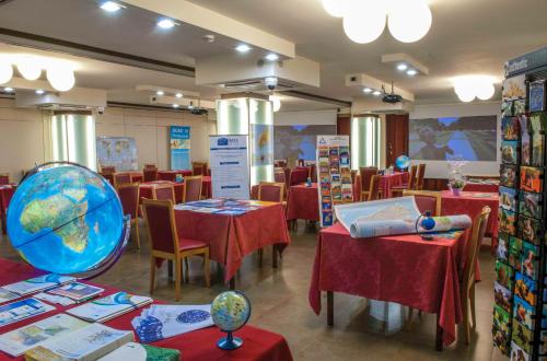 a restaurant with red tables and a globe on the table at Hotel La Bussola in Novara