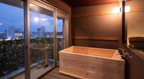 une baignoire en bois dans une pièce avec une fenêtre dans l'établissement Tamana Onsen Ryuganji Onsen Hotel, à Tamana
