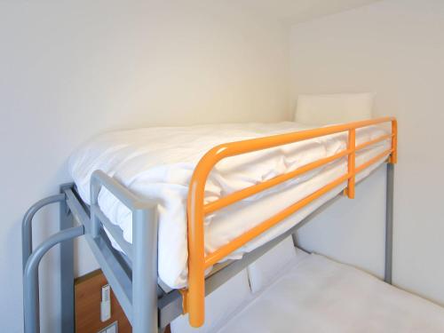 a bunk bed in a room with white sheets at Comfort Inn Nagasaki Airport in Omura