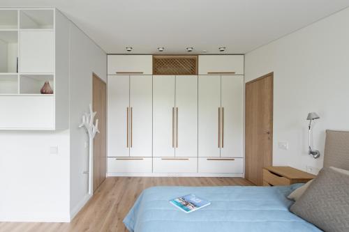 a living room with a bed and white cabinets at Aura apartamentai in Druskininkai