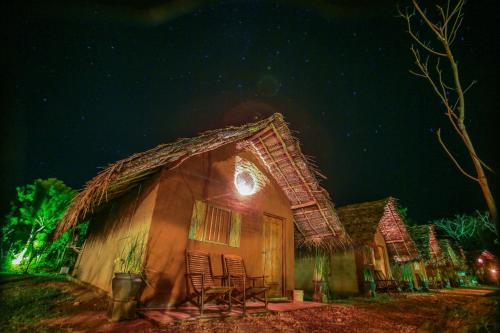 a house with a thatched roof at night at Gaga Bees Yala in Tissamaharama