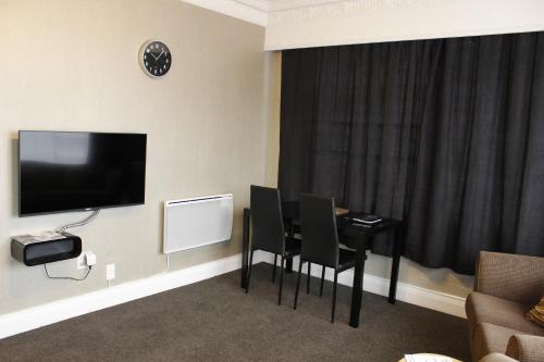 a living room with a table and chairs and a television at Colonial Motel in Invercargill