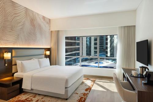 a bedroom with a bed and a desk and a window at Marriott Hotel Production City, Dubai in Dubai