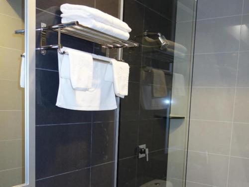 a bathroom with a glass shower with white towels at One Avenue Hotel (IJM) in Bandar Indah