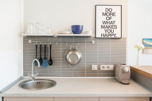 Una cocina con fregadero y un cartel que dice haz más de lo que te hace sentir bien. en Cluj Napoca Apartments, en Cluj-Napoca