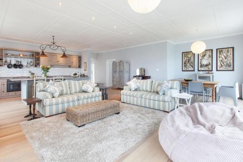 a living room with two couches and a kitchen at The Cove in Fish Hoek