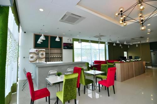 un restaurant avec des chaises rouges et vertes et un bar dans l'établissement Le Garden Hotel Kota Kemuning Shah Alam, à Kampong Bukit Naga