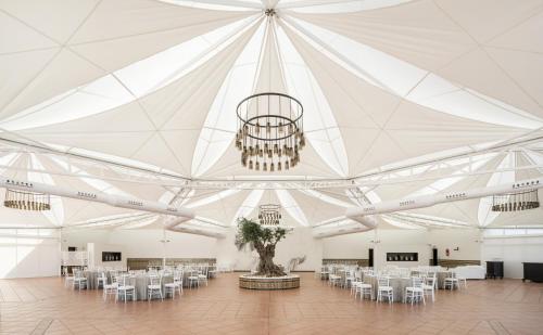 a large white tent with tables and chairs and a chandelier at Hotel Ilunion Las Lomas in Merida