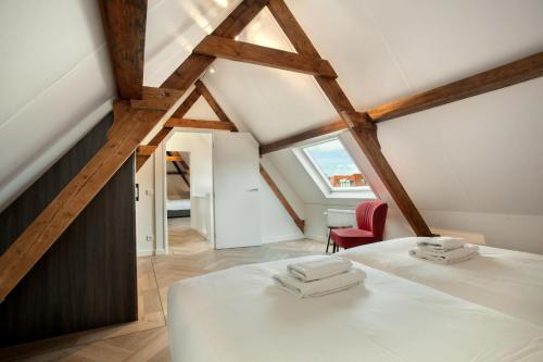 a attic bedroom with a bed and a red chair at Stayci Serviced Apartments Denneweg in The Hague