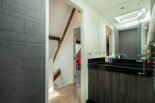 een badkamer met een zwarte wastafel en een spiegel bij Stayci Serviced Apartments Denneweg in Den Haag