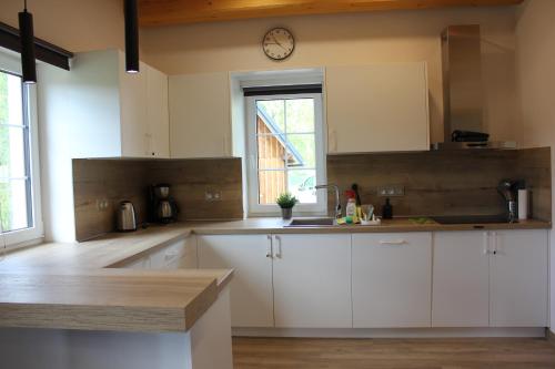 a kitchen with white cabinets and a clock on the wall at Roubenka Lučany in Lučany nad Nisou