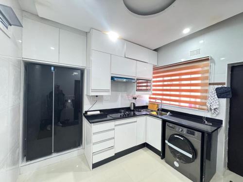 eine kleine Küche mit weißen Schränken und einem Geschirrspüler in der Unterkunft Poinsettia White House in Livingstone