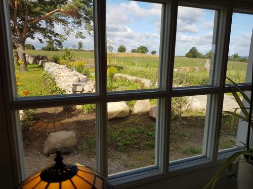 a window with a view of a field seen through it at Bästekille Gårdshotell in Kivik