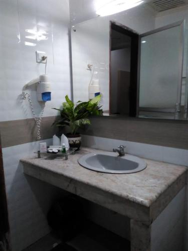 a bathroom counter with a sink and a mirror at Hotel Taufina Solok in Solok
