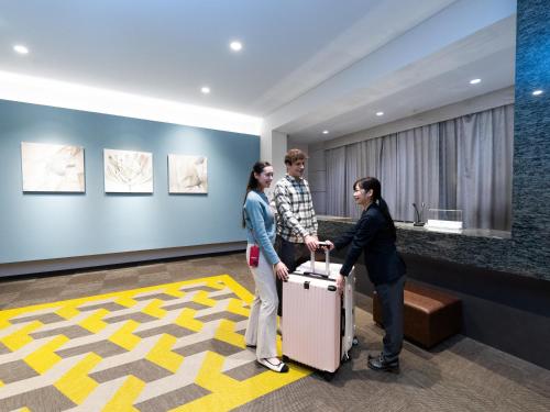 three people standing in a lobby with a suitcase at Tokyu Stay Suidobashi in Tokyo